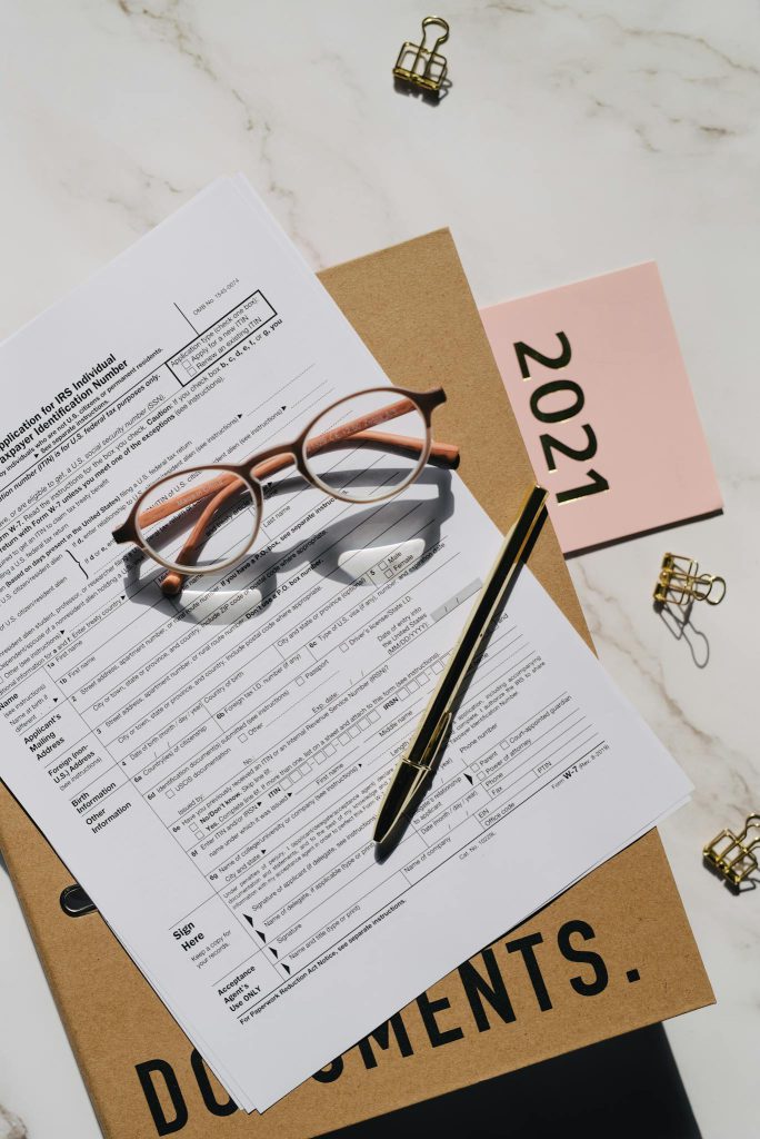 Close-up of tax forms, glasses, and pen on a desk, perfect for financial content.